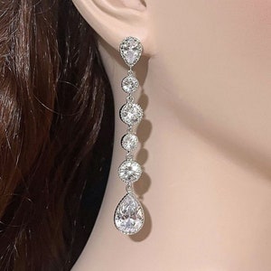 May include: Silver dangle earrings with a pear-shaped crystal and round crystals.