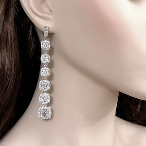 May include: Silver dangle earrings with a row of clear square cubic zirconia stones.