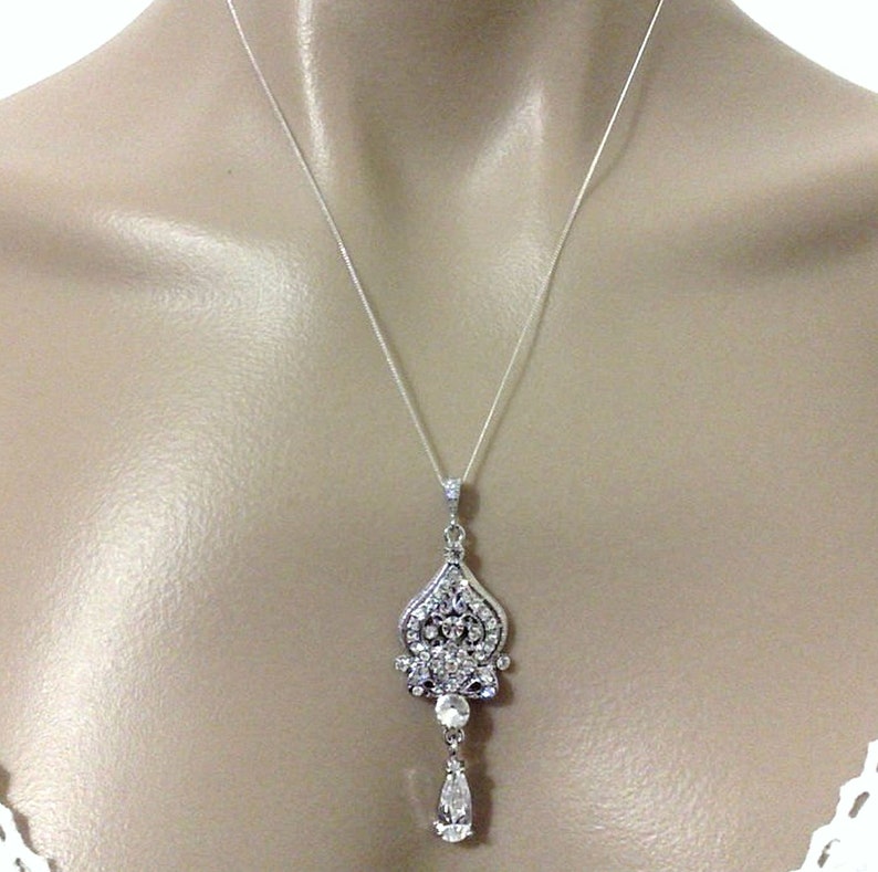 Puede incluir: Un collar de plata con un colgante en forma de l&aacute;grima adornado con brillantes transparentes. El colgante presenta un dise&ntilde;o delicado e intrincado.