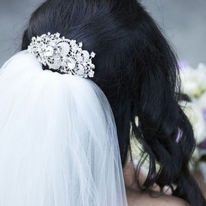 May include: A white bridal veil with a sparkling rhinestone hair comb. The veil is made of soft tulle and is perfect for a wedding.