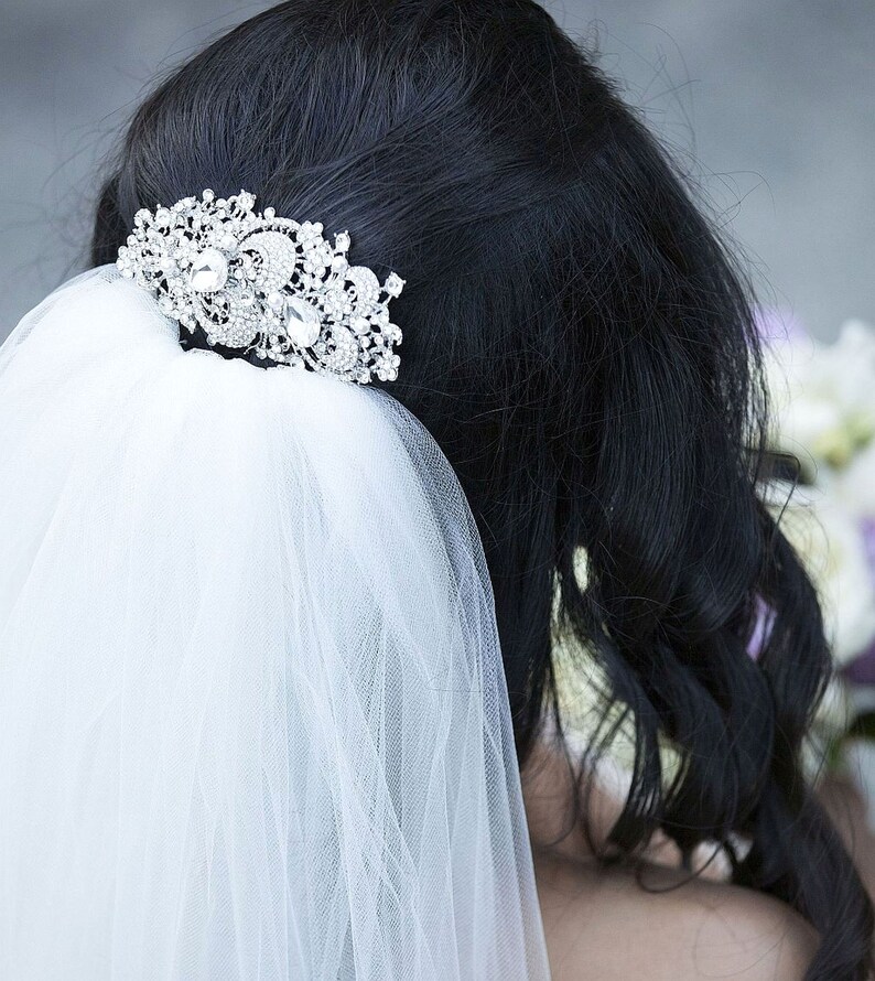 May include: A white bridal veil with a sparkling rhinestone hair comb. The veil is made of soft tulle and is perfect for a wedding.