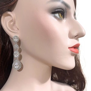 May include: Silver dangle earrings with a pear-shaped crystal and round crystals.