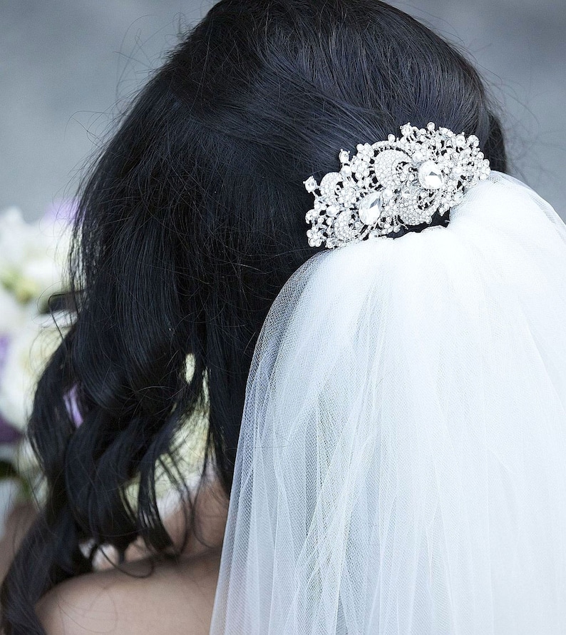 May include: A white bridal veil with a silver and crystal hair comb. The veil is made of soft tulle and is perfect for a wedding.