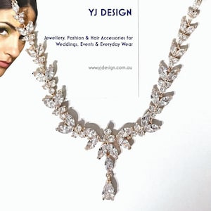 May include: Rose gold-toned necklace and headpiece with clear, sparkling crystal accents. The jewelry features a leaf-like design and a teardrop pendant. The image includes the text "YJ DESIGN" and "Jewellery, Fashion & Hair Accessories for Weddings, Events & Everyday Wear."