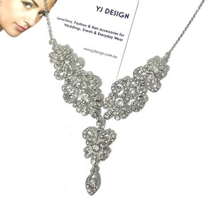 May include: Silver necklace with a large, ornate pendant featuring a butterfly design. The pendant is covered in clear rhinestones and hangs from a delicate chain.