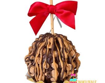 May include: A chocolate and peanut butter caramel apple with a red bow on top. The apple is on a gold paper wrapper.