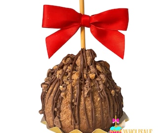 May include: A chocolate-covered caramel apple with a red bow on top. The apple is covered in chocolate and caramel, and there are nuts on top. The apple is on a gold paper wrapper.