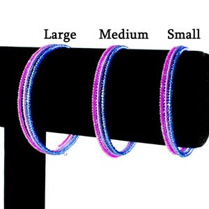 May include: Three beaded bracelets in different sizes, labeled "Large", "Medium", and "Small". The bracelets are made of small, iridescent beads in shades of pink and blue.