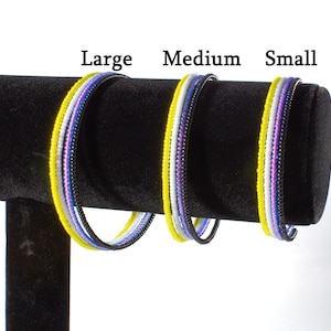 May include: Three beaded bracelets in different sizes, labeled "Large", "Medium", and "Small". The bracelets are made with yellow, white, purple, and black beads.