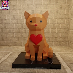 May include: A geometric papercraft cat sculpture in shades of tan, with a red heart on its chest. The cat sits on a black marble base. The logo "PAPERCRAFT DREAM" is in the upper left corner.