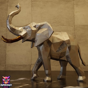 May include: A low-poly geometric elephant sculpture featuring a metallic silver finish and prominent gold-coloured tusks. The figure is depicted in a walking stance with its trunk raised upward, showcasing sharp angular facets throughout its body.