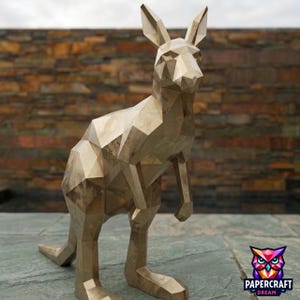 Peut inclure: Une sculpture de kangourou géométrique de couleur dorée, présentant un design à facettes en low-poly avec des angles vifs et des surfaces planes. La figurine se tient debout avec des oreilles pointues et une longue queue, finition métallique.