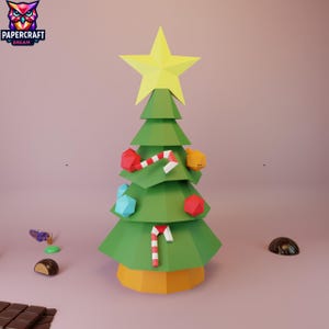 以下が含まれることがあります： 黄色の星が付いた緑色の紙のクリスマスツリー。幾何学的な装飾品とキャンディケインで飾られています。ツリーは黄色のベースにあります。Papercraft Dreamのロゴが左上にあります。