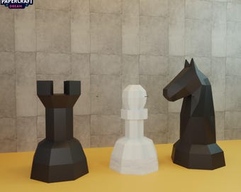 Puede incluir: Tres piezas de ajedrez geométricas: una torre negra, un peón blanco y un caballo negro. Las piezas están sobre una superficie amarilla y una pared texturizada de color marrón claro. El logotipo "PAPERCRAFT DREAM" está en la esquina superior izquierda.