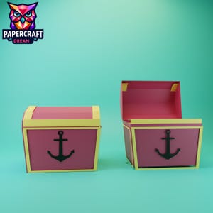 Pode incluir: Dois baús de tesouro de papel, um aberto e outro fechado, em tons de vermelho e amarelo. Cada baú apresenta um desenho de âncora preta na frente. Os baús estão sobre um fundo azul-turquesa, com o logotipo Papercraft Dream no canto superior esquerdo.