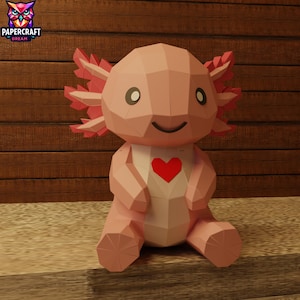 Peut inclure: Un axolotl rose en papier avec un cœur rouge sur la poitrine. L'axolotl a un visage souriant et des branchies roses. Le logo Papercraft Dream est en haut à gauche. L'axolotl est assis sur une surface marron clair avec un fond en bois.