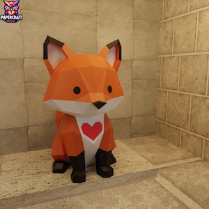 Puede incluir: Un zorro de papel geométrico en tonos naranja, blanco y negro, con un corazón rojo en el pecho. El zorro tiene orejas grandes y está sentado erguido. El logotipo de Papercraft Dream está en la esquina superior izquierda.