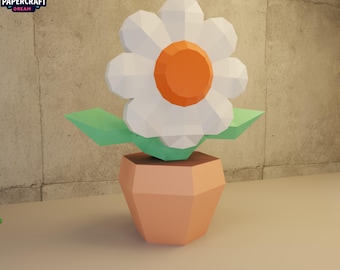 May include: A papercraft flower in a pot. The flower has white petals and an orange center. The leaves are green, and the pot is peach-colored. The Papercraft Dream logo is in the upper left corner.