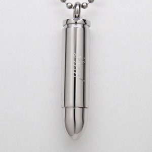 May include: A silver bullet-shaped pendant necklace with a chain. The pendant has the word "Mom" engraved on it.