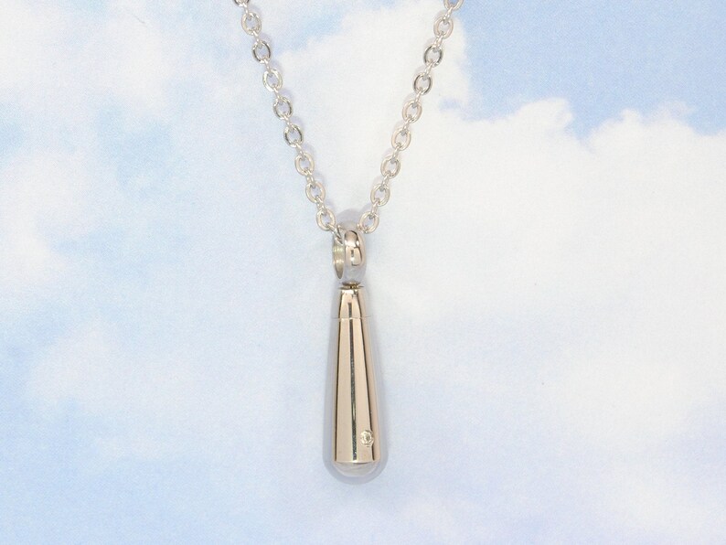 May include: A silver teardrop-shaped pendant necklace. The pendant is on a silver chain.