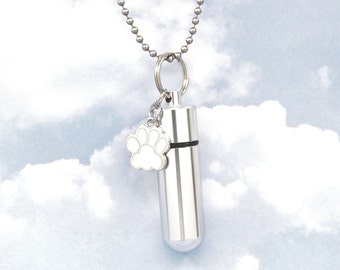 May include: Silver necklace with a small paw print charm and a cylindrical cremation urn pendant. The necklace is on a white background.