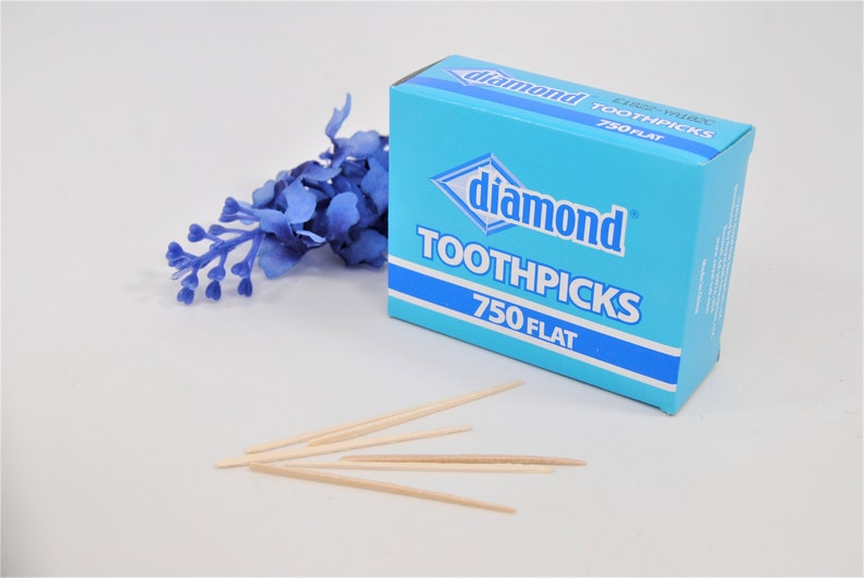 May include: A blue box of Diamond toothpicks with the text "750 Flat" on the front. A small pile of wooden toothpicks is in the foreground.