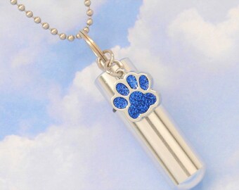 May include: Silver necklace with a small silver cylinder charm that has a blue glitter paw print on it.