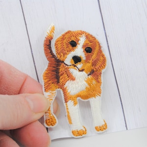 May include: Embroidered iron-on patch of a brown and white beagle dog with a white background.