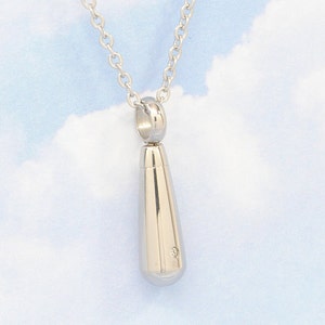 May include: A silver teardrop-shaped pendant necklace with a small diamond accent. The necklace is on a silver chain.