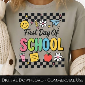 Puede incluir: Camiseta gris claro con un diseño colorido de "First Day Of SCHOOL". El diseño incluye una carita sonriente, un lápiz, una flor, un avión de papel, una taza de café, un bloc de notas, una manzana y estrellas. La camiseta tiene un patrón de cuadros.