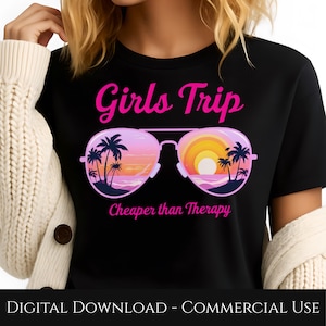 Puede incluir: Camiseta negra con la frase "Girls Trip" en rosa sobre un gráfico de gafas de sol. Las lentes de las gafas de sol muestran una escena de atardecer con palmeras y el texto "Cheaper than Therapy" debajo.