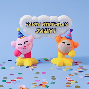 May include: A vibrant birthday cake topper with two cartoon figures, one pink and one orange, supporting a cloud-shaped sign that reads "HAPPY BIRTHDAY JAMY!". The characters wear party hats and stand on yellow star-shaped bases.