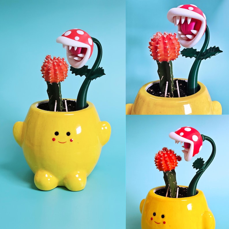 May include: A yellow ceramic plant pot in the shape of a character with a smiling face, holding a cactus and a decorative Piranha Plant with a red and white spotted head. The background is a light blue. The pot has small arms and legs.