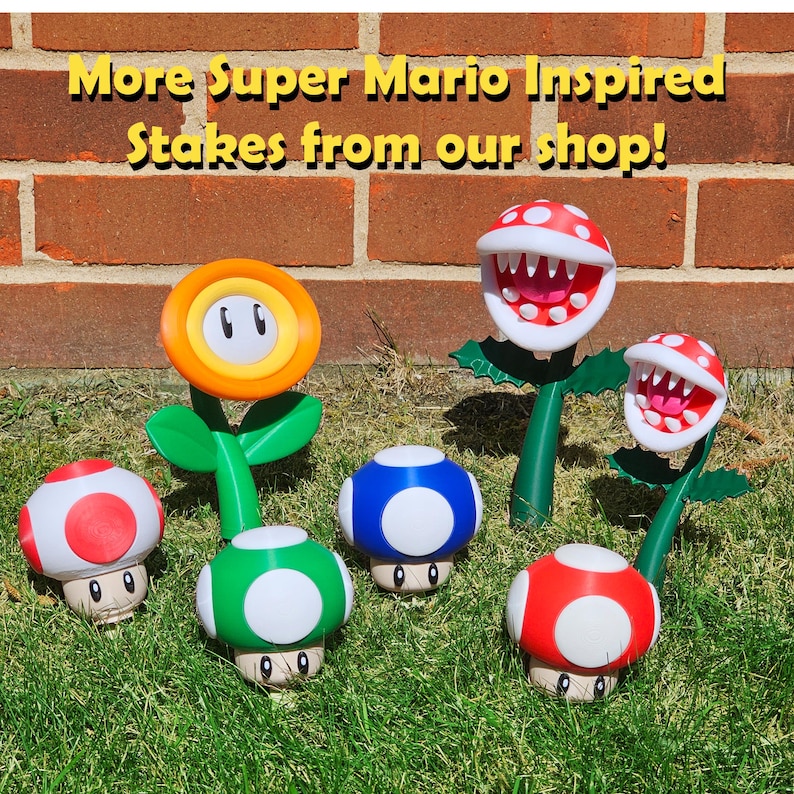 May include: A selection of Super Mario-themed garden stakes, featuring a yellow flower, red and white mushrooms, a green mushroom, a blue mushroom, and two Piranha Plants. The stakes are displayed on grass in front of a brick wall. The text reads "More Super Mario Inspired Stakes from our shop!"