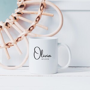 May include: White ceramic mug with a black cursive design that says "Olivia Wilson".