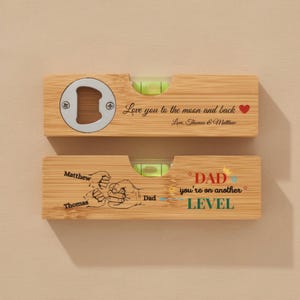 May include: Two wooden bottle opener levels. One has a bottle opener and the text "Love you to the moon and back". The other says "DAD you're on another LEVEL" with a fist bump graphic. Both have a bubble level.