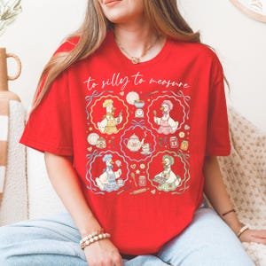 May include: Red t-shirt with the phrase "to silly to measure" in cursive. The shirt features a whimsical design of cartoon geese in chef hats and aprons, surrounded by kitchen-themed illustrations.