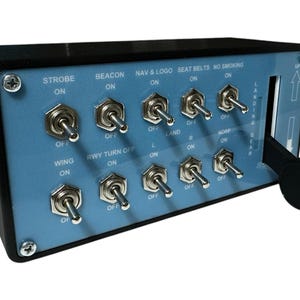 May include: A blue panel with a variety of toggle switches and labels, including "Strobe", "Beacon", "Nav & Logo", "Seat Belts", "No Smoking", "Wing", "Rwy Turn Off", "Land", "Nose", and "Landing Gear".