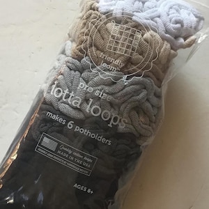 May include: A package of three sets of gray, beige, and white yarn loops. The package is labeled "pro size lotta loops" and "makes 6 potholders". The package also says "friendly loom" and "quality cotton loops made in the USA".