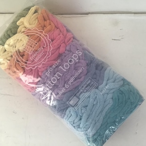 May include: A bag of colorful cotton loops in shades of green, yellow, orange, pink, purple, and blue. The bag is labeled "friendly loom pro size cotton loops makes 6 potholders".