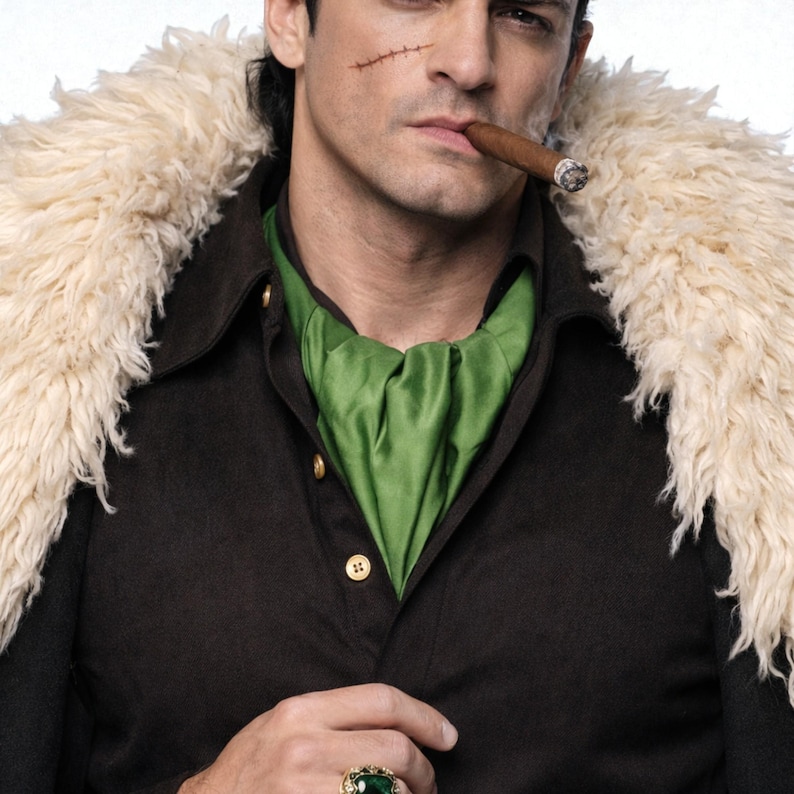 May include: A person wearing a dark brown coat with a cream-colored fur collar and a green scarf. The person is smoking a cigar and wearing a gold ring with a green stone. A scar is visible on the person's face.