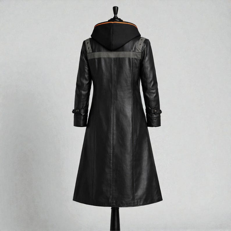 May include: A long, black leather coat with a hood. The coat has a tailored fit, buttoned cuffs, and a grey stripe across the upper back. The hood has an orange trim. The coat is displayed on a black mannequin.