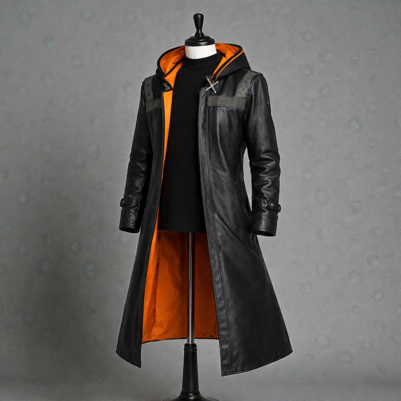 May include: A long black leather coat with an orange lining and hood. The coat has a high collar, a cross-shaped clasp, and grey shoulder accents. The coat is displayed on a mannequin.