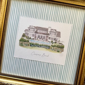 Puede incluir: Pintura a la acuarela enmarcada de una casa con piscina, sobre un fondo a rayas azul claro y blanco. El marco dorado tiene un diseño ornamentado. El texto "Cousins Beach" está escrito debajo de la casa en la pintura.