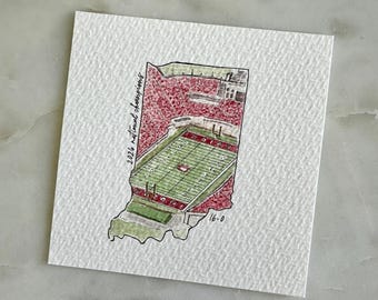 May include: Watercolor illustration of Indiana in the shape of the state, featuring a football stadium. The stadium has red seating and a green field. Text reads "2026 national champions" and "16-0".