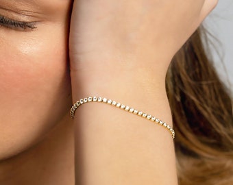 May include: A gold bracelet with small, clear stones set in a delicate chain.