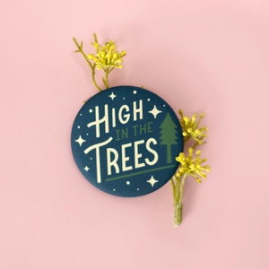 May include: A blue button with white text that reads "High in the Trees" and a green pine tree graphic. The button has white stars around the edge.