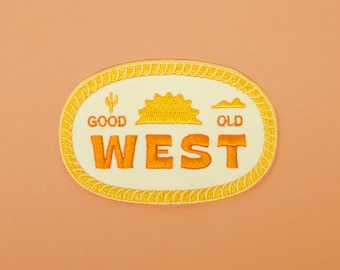 Puede incluir: Un parche bordado amarillo y naranja con las palabras "Good Old West" en un óvalo blanco con un borde de cuerda. El parche presenta un cactus, un sol y una montaña.
