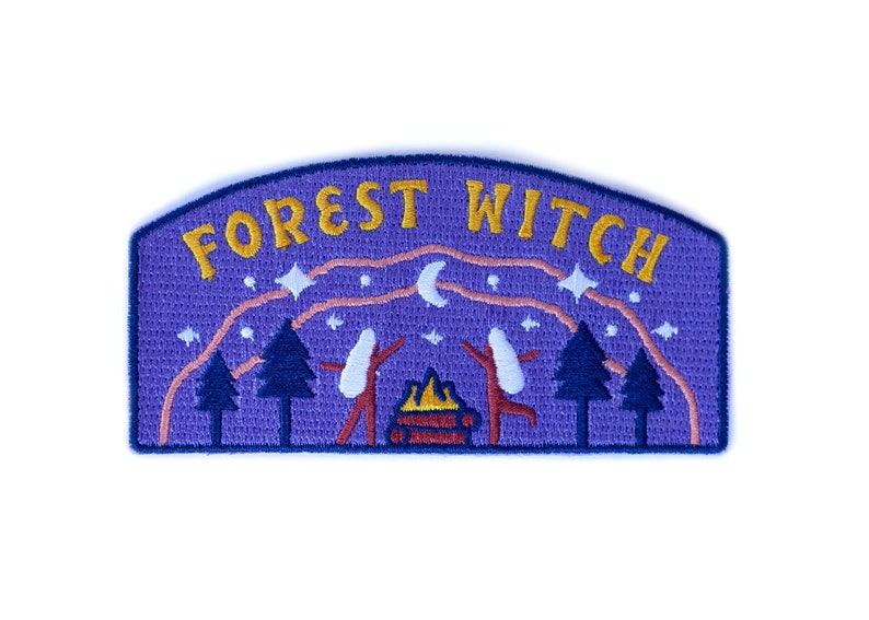 K&ouml;nnte beinhalten: Gestickter Aufn&auml;her mit lila Hintergrund und den Worten "FOREST WITCH" in Gold. Das Design umfasst ein Lagerfeuer, B&auml;ume, Sterne und zwei Figuren mit erhobenen Armen. Der Aufn&auml;her hat einen blauen Rand.