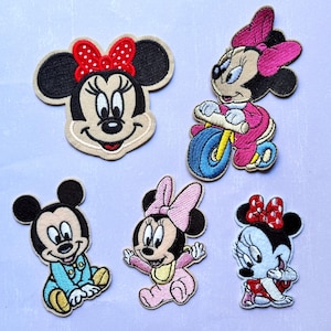 Può includere: Una collezione di toppe ricamate raffiguranti il personaggio di Minnie Mouse in varie pose. Le toppe mostrano l'aspetto iconico di Minnie con le sue grandi orecchie nere, il fiocco rosso e il viso sorridente. Alcune toppe raffigurano Minnie su un triciclo o in abiti da neonato.